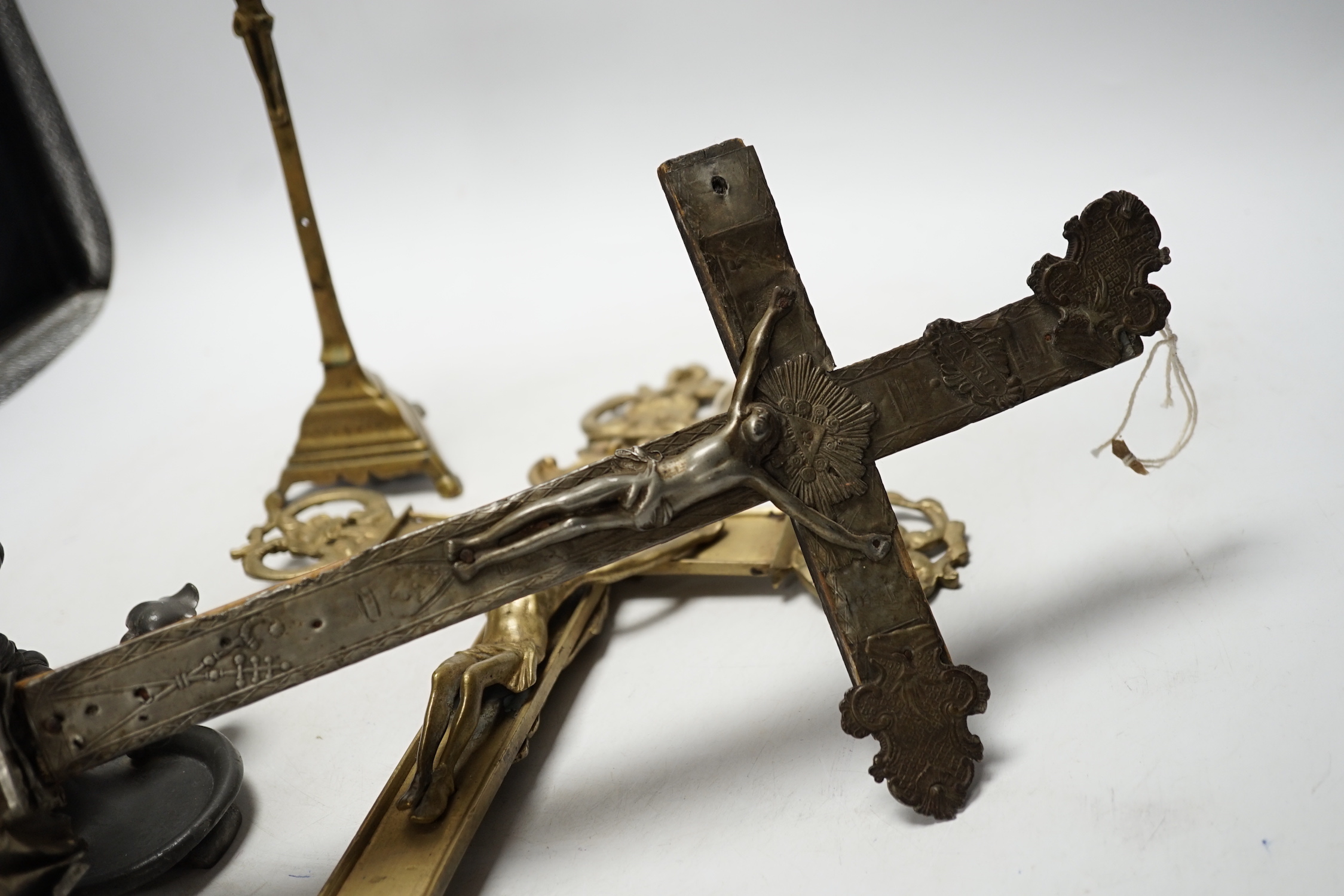 Three brass crucifixes and an Orivit pewter candlestick, tallest 45cm high